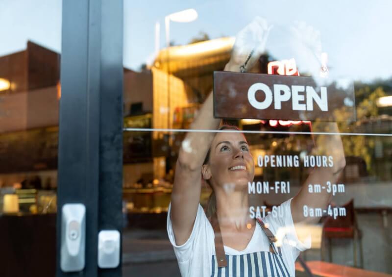 Self employed shop worker opening shop with open sign