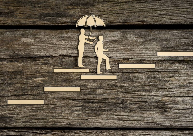 Two silhouettes walking up staircase with insurance umbrella